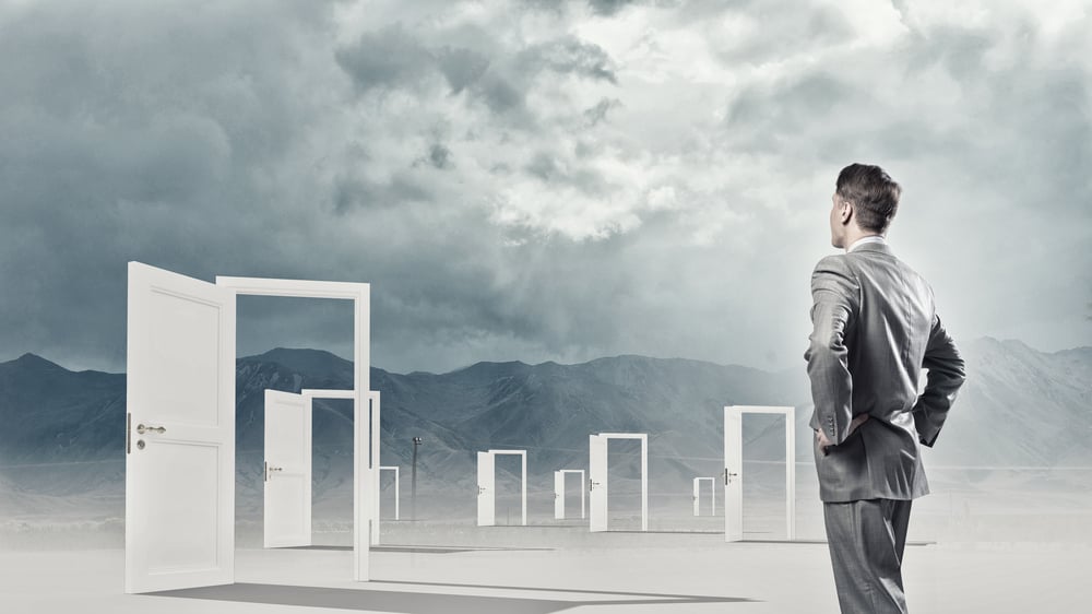 Businessman standing in front of opened doors and making decision Businessman standing in front of opened doors and making decision