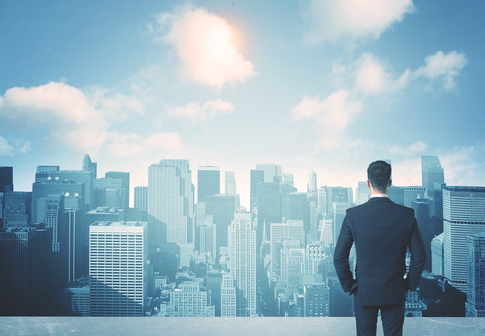 Businessman standing on a roof and looking at future city Businessman standing on a roof and looking at future city
